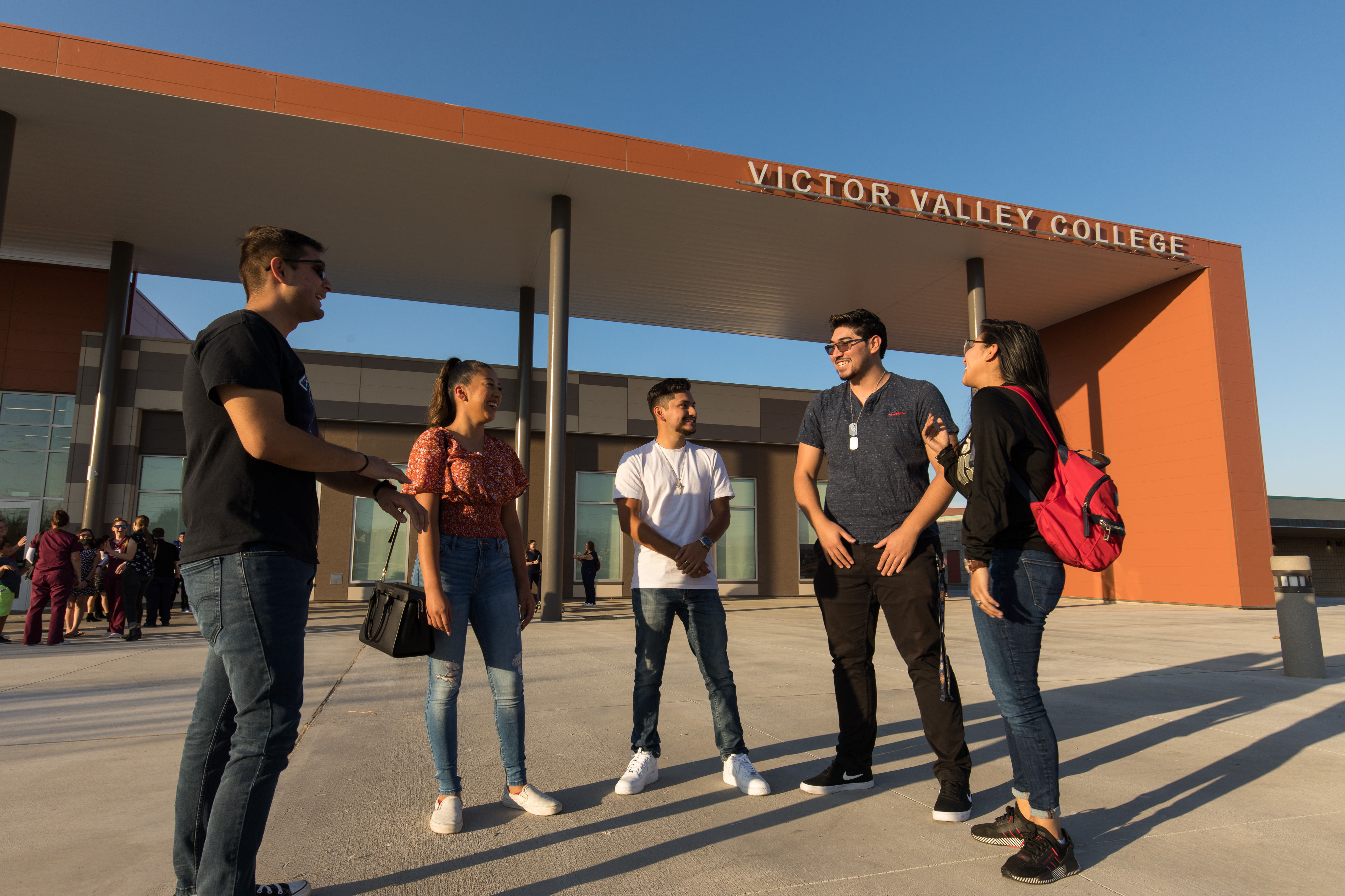 Five students having a discussion in front of a building on the VVC campus.