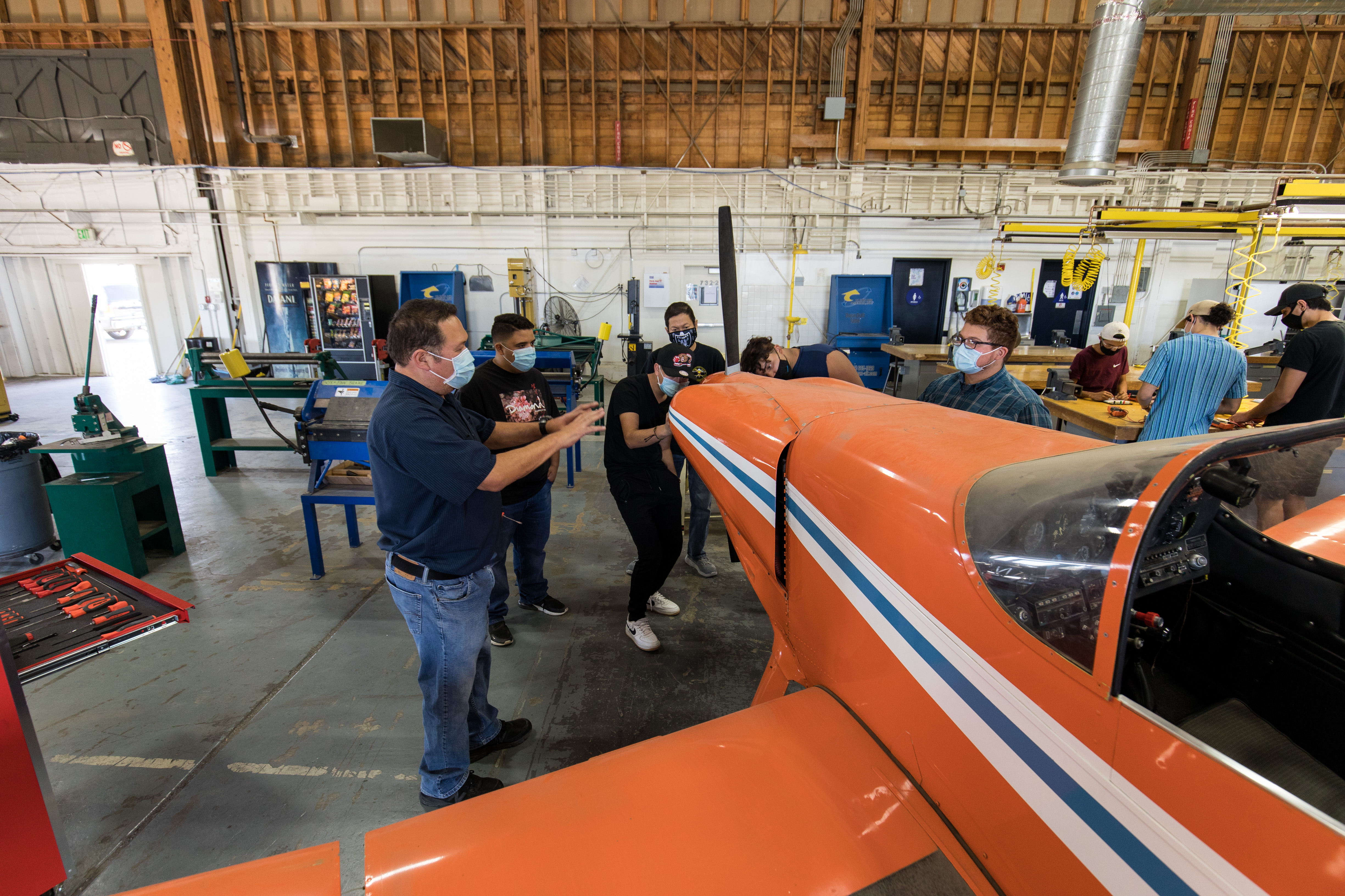 Group of students and a professor looking at and working on an airplane. 