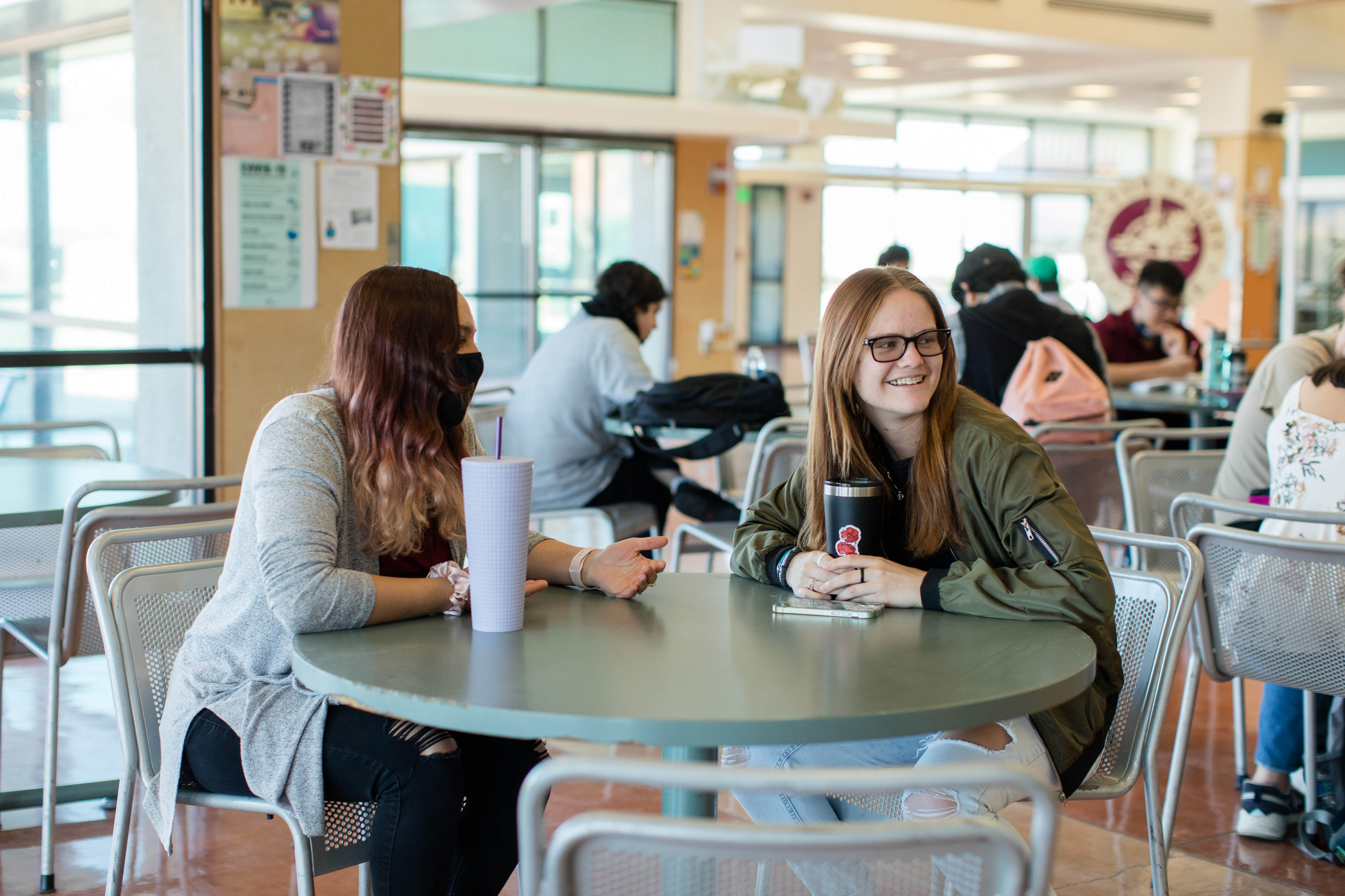 Two students sitting at a table with drinks. 