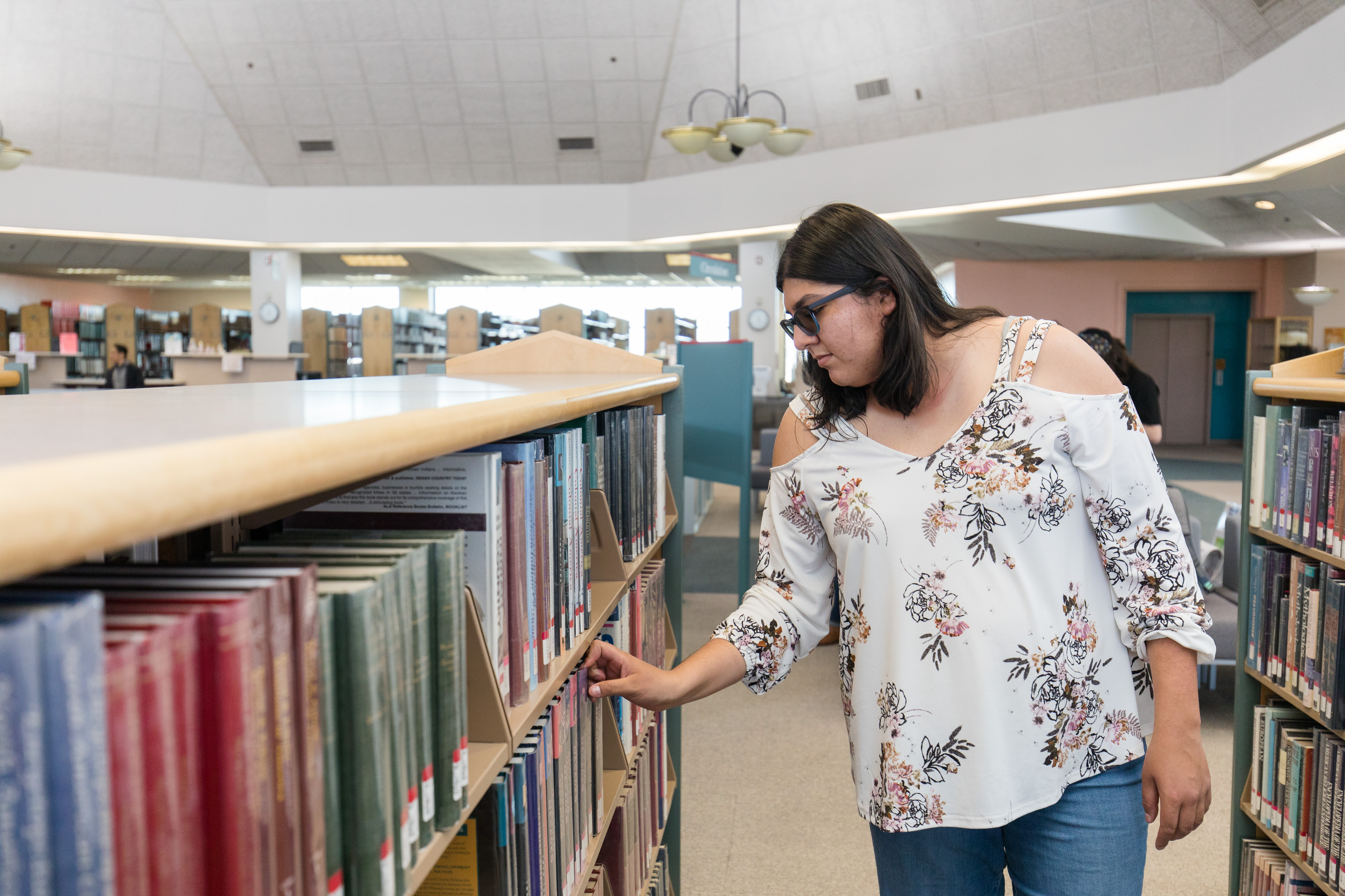 Student looking for a book on a bookshelf in the VVC library. 